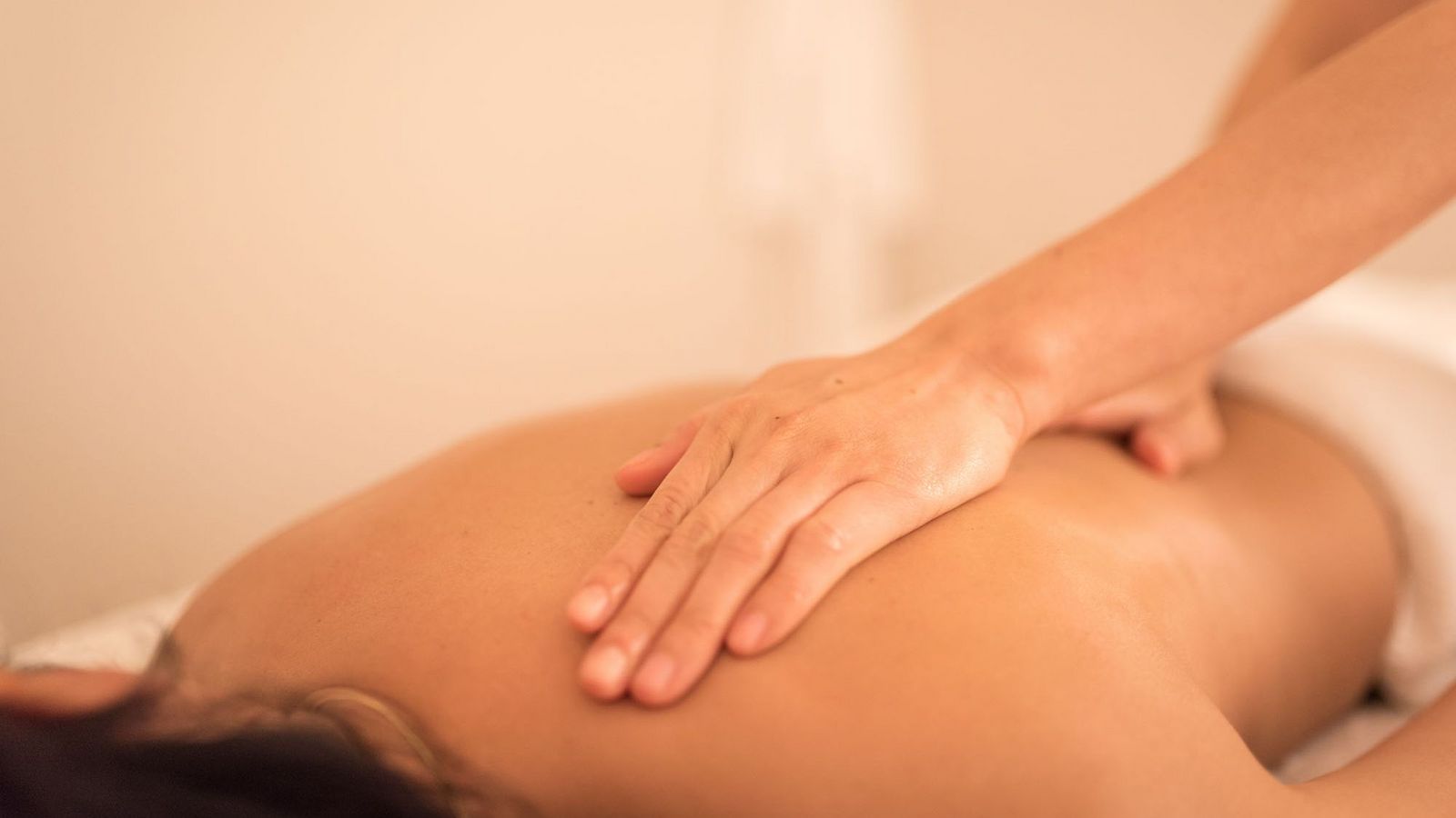 Bei einer Rückenmassage legt der Therapeut die Hände auf das Schulterblatt und den Rücken der Patientin