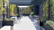 Tische und Stühle auf einer Dachterrasse, die durch zahlreiche Pflanzen begrünt ist