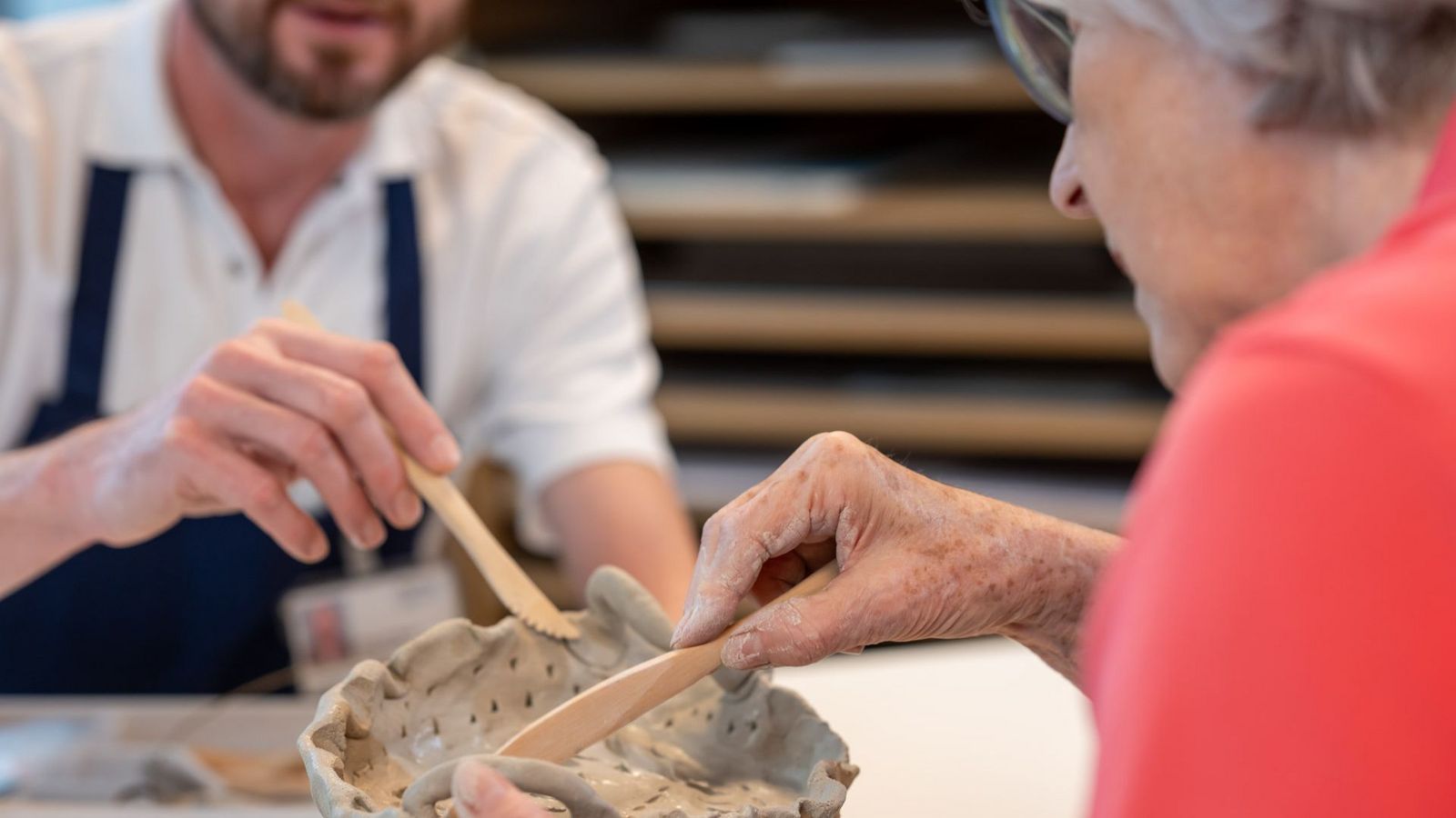 Eine Patientin formt Ton mit einem Holzspachtel