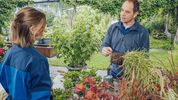 Der Gartentherapeut erklärt der Patientin anhand einer Pflanze, was sie beachten muss