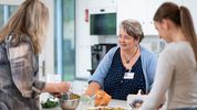 Eine Ergotherapeutin bereitet mit zwei Patientinnen eine Zwetschgenwähe vor