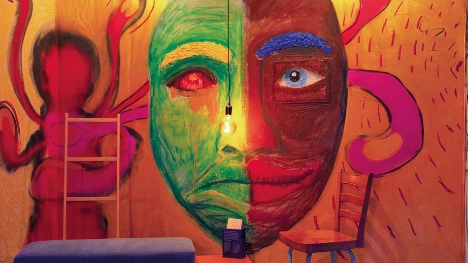 Bemalte Wand mit einem abstrakten Gesicht, das in eine grüne und eine rote Hälfte geteilt ist