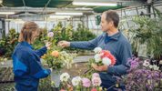 Therapeut und Patientin stellen einen Strauss mit weissen und rosaroten Blumen zusammen