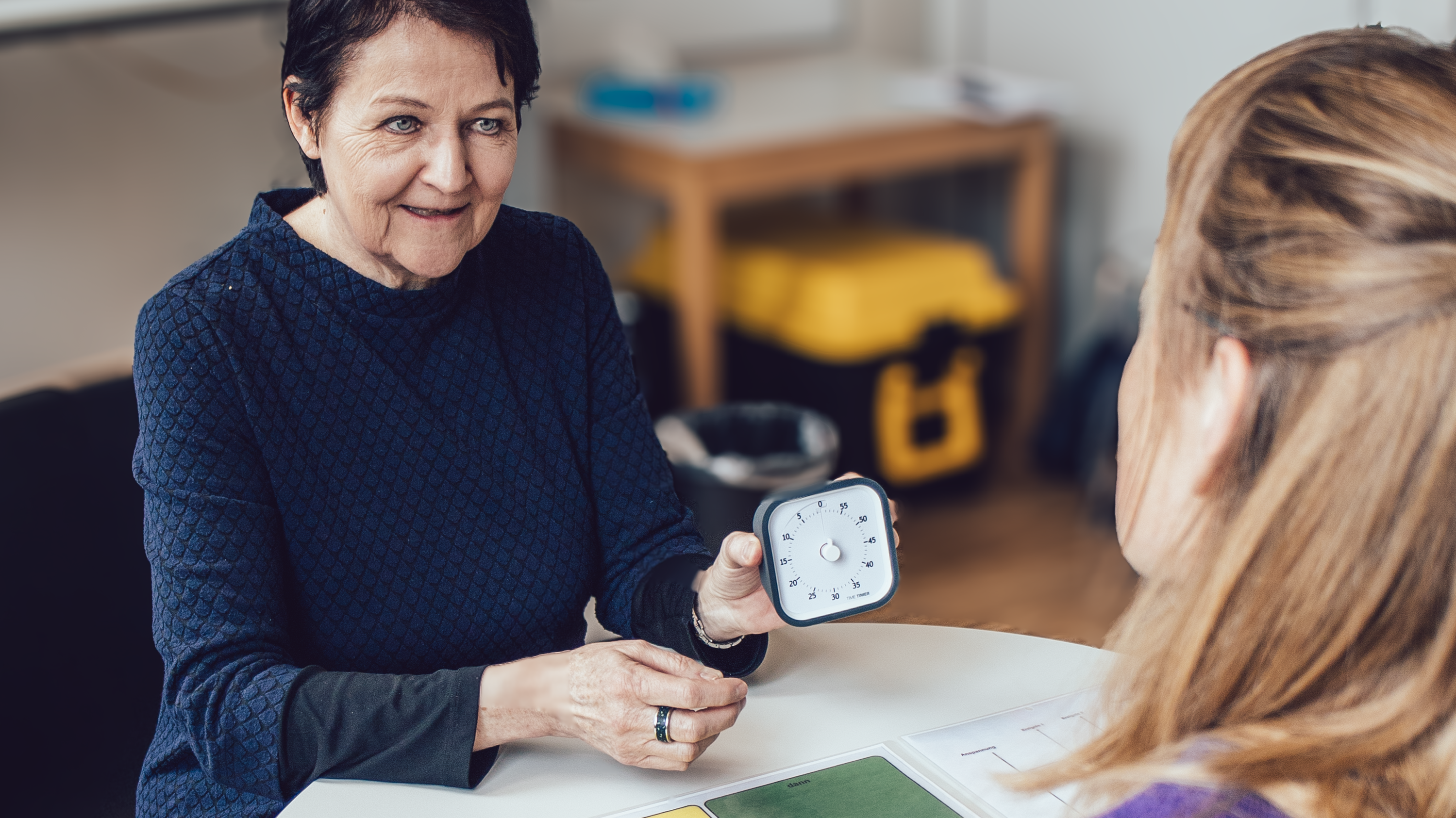 Patricia Fragnito, IAS, zeigt einer Lehrperson, wie man mit einer Uhr Zeit visualisieren kann.