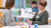 Die Arbeitstherapeutin erklärt den nächsten Schritt beim Nähen
