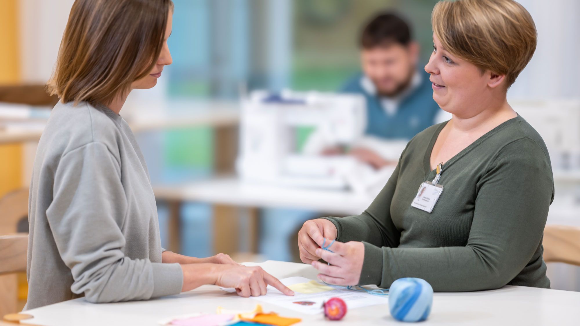 Die Arbeitstherapeutin erklärt den nächsten Schritt beim Nähen