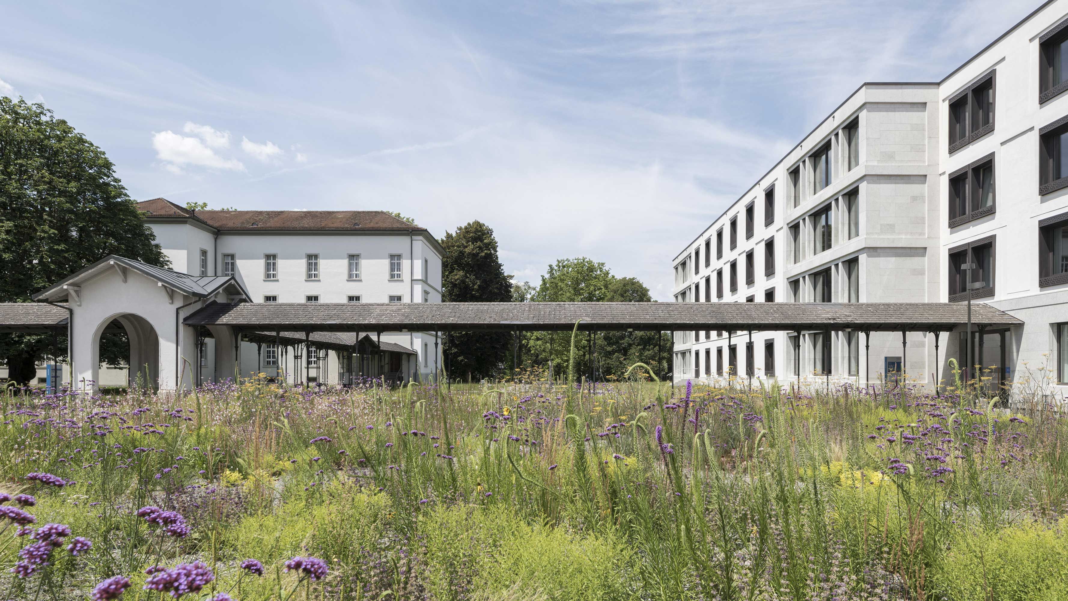 Ein überdachter Durchgang verbindet das historische Klinikgebäude mit dem modernen Neubau