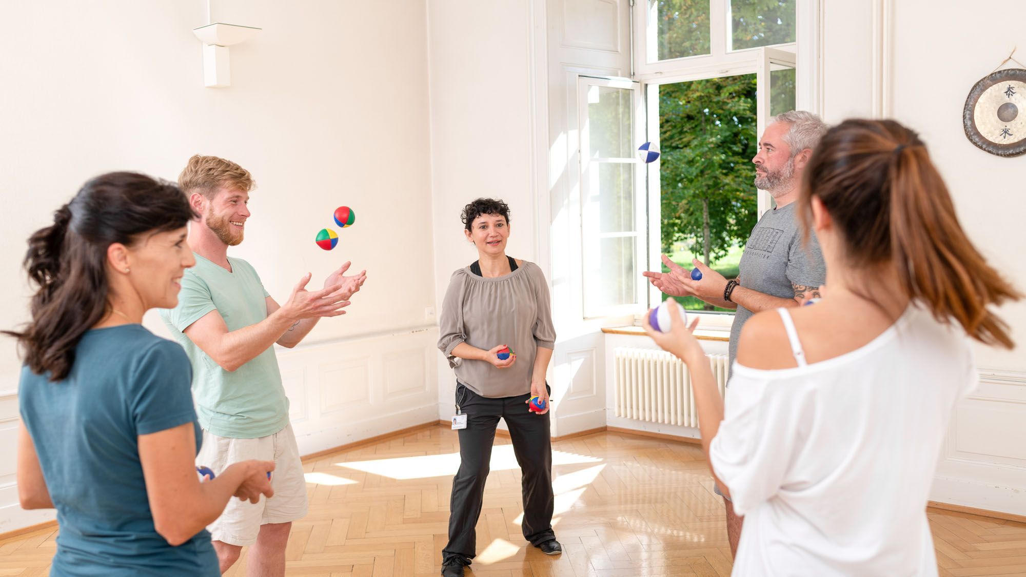 Eine Therapeutin bringt einer Gruppe da Jonglieren bei