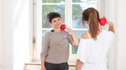Die Therapeutin demonstriert eine Nackenübung mit einem kleinen Ball