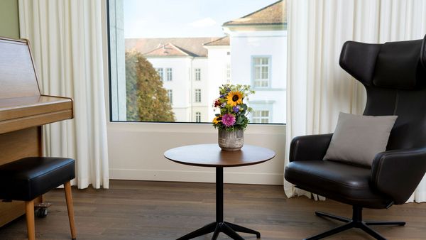 Aufenthaltsraum mit Klavier, Sessel und Blick auf das Areal