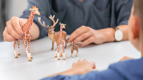 Eine Therapeutin und ein Kleinkind im Spielsetting mit Plastikgiraffen