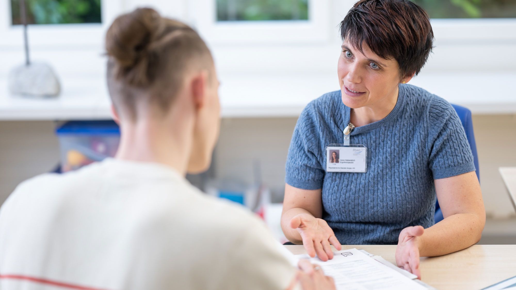 Eine Ergotherapeutin geht mit einem Patienten eine Checkliste durch