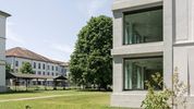 Zwischen dem modernen Neubau mit seinen bodentiefen Fenstern und dem historischen Gebäude mit seiner weissen Fassade steht ein über 15 Meter grosser Baum