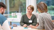 Eine Therapeutin arbeitet mit zwei Patienten im Nähatelier