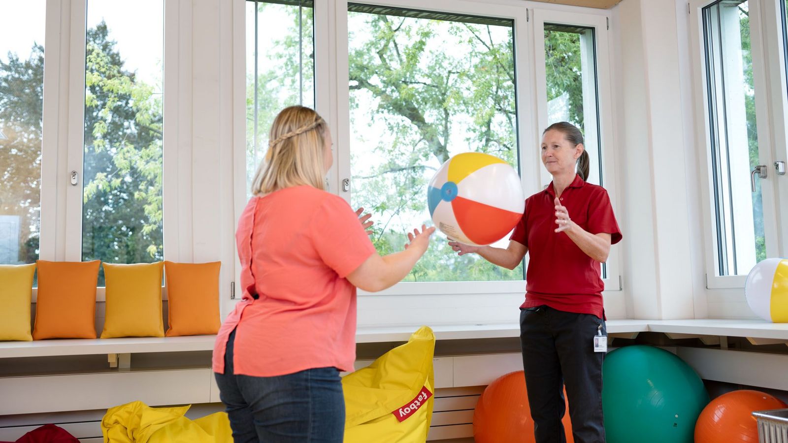 Eine Patientin wirft einer Therapeutin einen bunten Ball zu
