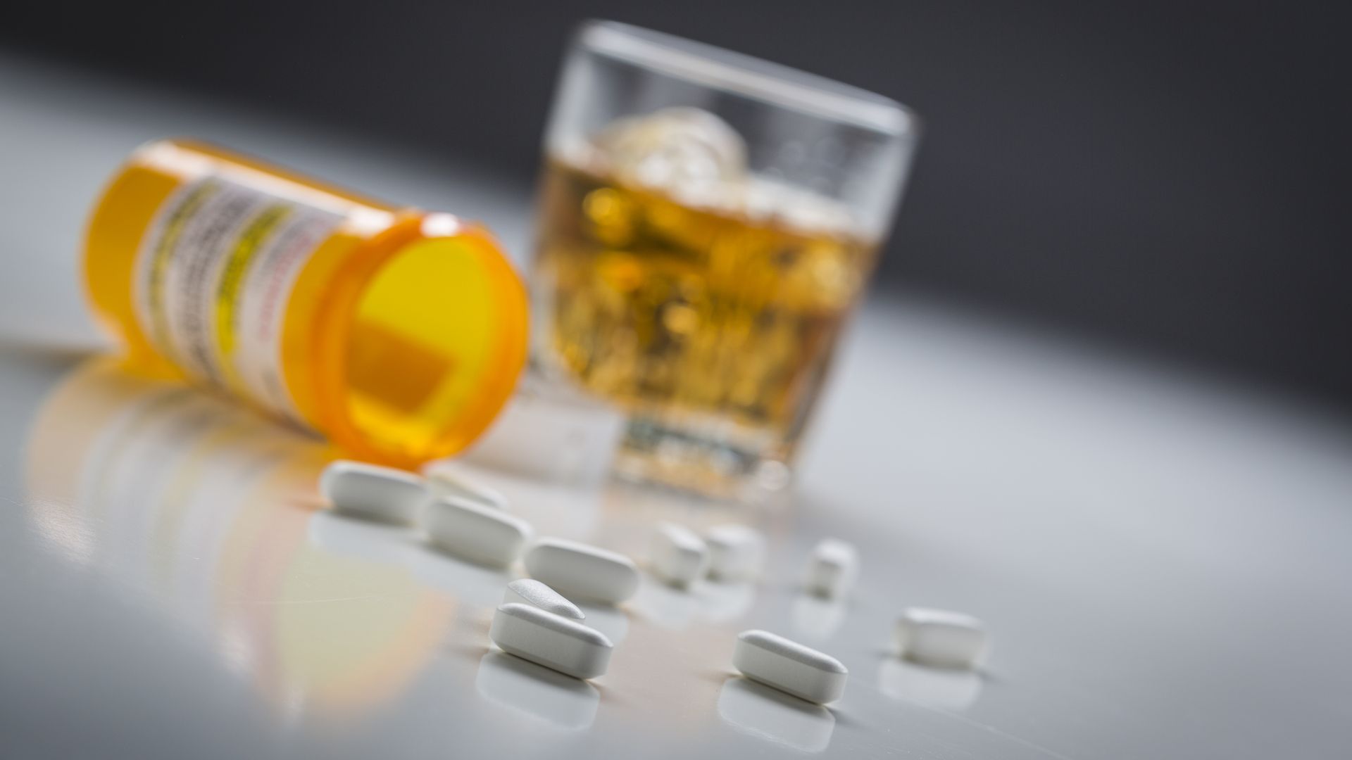 Eine Dose mit Tabletten und ein Glas mit Alkohol stehen auf einem Tisch